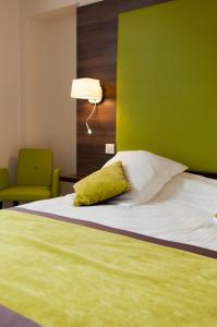 a bed with a green headboard and a green wall at Logis Hotel du Parc-Restaurant - Le Rouget de Lisle in Lons-le-Saunier