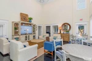 a living room with chairs and a tv and tables at Ocean Club E-301 in Indian Beach