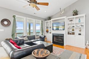 a living room with a leather couch and a fireplace at Luxury Sands in Emerald Isle