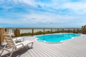 a deck with a swimming pool and a chair and the ocean at Luxury Sands in Emerald Isle