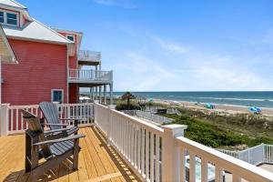 a house with a deck with a chair and the beach at Loving Life East in Emerald Isle