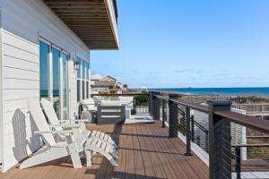 a porch with white chairs and a view of the ocean at Fair Winds East in Cape Carteret