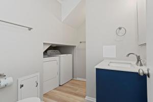 a white kitchen with a sink and a blue cabinet at Carolina Clipper West in Emerald Isle +26 photos