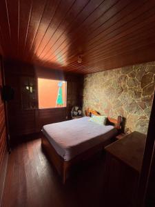 a bedroom with a bed in a stone wall at Casa de Madeira com piscina e churrasqueira in Araruama