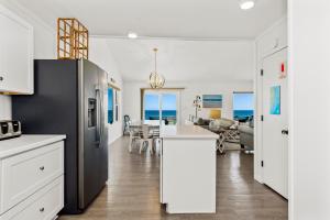 a kitchen and dining room with the ocean in the background at Carolina Clipper East in Emerald Isle