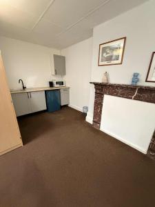 an empty room with a fireplace and a kitchen at Budget Studio - Central Gosport with Free Parking in Gosport