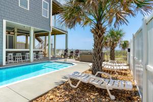 a swimming pool with a palm tree next to a house at Sea Worthy in Indian Beach