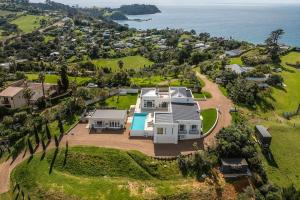 eine Luftansicht eines Hauses auf einem Hügel neben dem Meer in der Unterkunft Onetangi Estate including cottage by Waiheke Pure in Waiheke Island