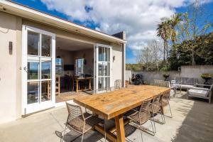 ein Holztisch und Stühle auf einer Terrasse in der Unterkunft Onetangi Estate including cottage by Waiheke Pure in Waiheke Island