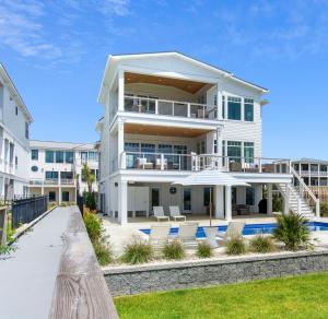 a large white building with chairs in front of it at Roosevelt Oceanfront Escape by Emerald Isle Realty in Pine Knoll Shores
