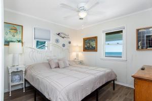 a white bedroom with a bed and two windows at Salty Haven in Emerald Isle