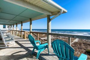 two green chairs sitting on a porch overlooking the beach at Salty Haven in Emerald Isle