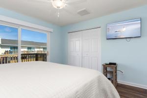 a bedroom with a bed and a tv on the wall at Pine Knoll Townes 126 by Emerald Isle Realty in Pine Knoll Shores