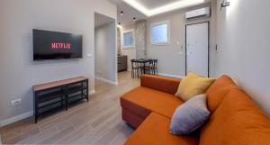 a living room with an orange couch and a tv at Casetta 48 in Lido di Ostia