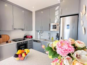 a kitchen with white cabinets and a bowl of fruit on a counter at Serenity by the Ocean Penthouse by BeCherish in Páteo