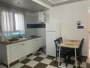 Una cocina con una mesa y un refrigerador blanco. en Appartement calme et lumineux, en Sousse