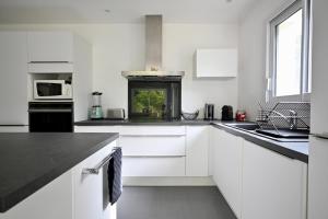 a kitchen with white cabinets and black counter tops at Maison moderne avec spa et jardin sans vis-à-vis, idéal professionnels et familles - L'ÉCRIN BRETON in Vannes