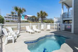 a patio with white chairs and a swimming pool at Aqua Vista in Emerald Isle