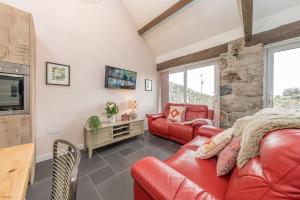 a living room with red leather furniture and a stone wall at Gorlan-Llangwnadl in Llangwnadl