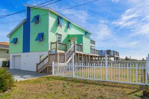 a green and blue house with a white fence at C-Life in Emerald Isle