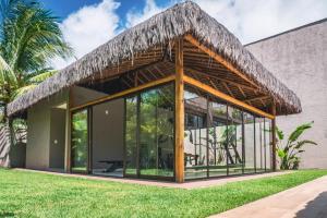 un pavillon avec un toit de chaume dans un bâtiment dans l'établissement Apê Praia do Toque com Ar no Quarto e Sala, Condomínio com Academia, Quadra de Beach Tennis e Vôlei, Estacionamento Grátis e Restaurante, à São Miguel dos Milagres