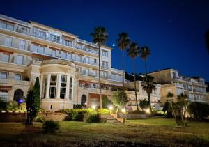 a large white building with palm trees in front of it at Le Gatsby 3 Etoiles - Tennis - Vue mer in Hyères