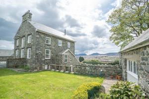una antigua casa de piedra con un patio de césped en Rheithordy, en Trawsfynydd
