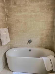 Una bañera blanca en un baño con toallas. en Aurora Executive Stay In Waterfall City, en Midrand