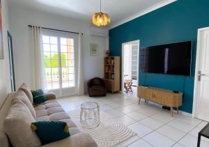 a living room with a couch and a flat screen tv at Le Gatsby 3 Etoiles - Tennis - Vue mer in Hyères