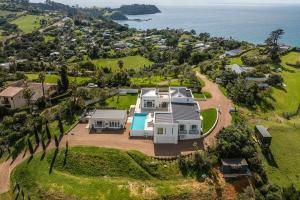 eine Luftansicht eines Hauses auf einem Hügel neben dem Meer in der Unterkunft Onetangi Estate by Waiheke Pure in Waiheke Island