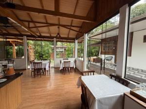 a dining room with tables and chairs and windows at Pousada Do Siri in Ilha do Mel