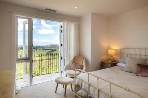 ein Schlafzimmer mit Bett und Balkon mit Aussicht in der Unterkunft Onetangi Estate by Waiheke Pure in Waiheke Island + 45 Fotos