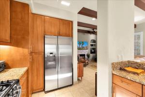 a kitchen with stainless steel refrigerator and wooden cabinets at Alluring Desert Haven in La Quinta #A in La Quinta +25 photos