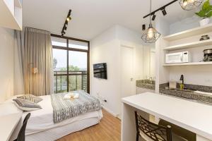 a room with a bed and a kitchen with a counter at Eco Smart - Ecoville | Gonzaga Stays in Curitiba +119 photos