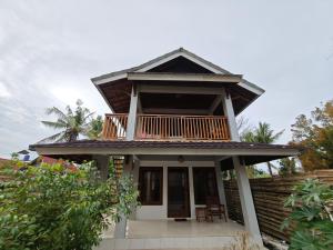 una casa con un balcón encima en Juna Bungalow, en Gili Air
