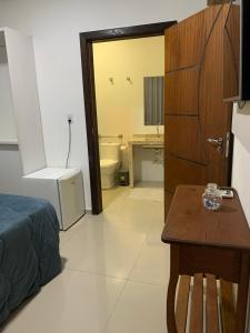 a bedroom with a bed and a bathroom with a toilet at Pousada Vô Nilo in Penha