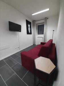 Una sala de estar con un sofá rojo y un televisor de pantalla plana. en La Stella Bianca, en Sutri
