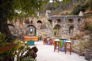 a patio with tables and chairs in front of a stone wall at Supertramp Hostel Cusco in Cusco