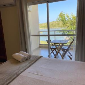 a bedroom with a bed and a balcony with a table at Pousada Peninsula Santa Rita in Guarapari