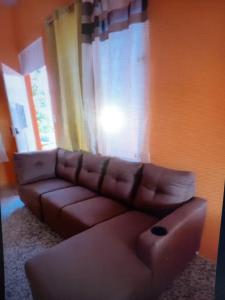 sala de estar con sofá marrón y ventana en Nuestra Casita Apartamento Rinconcito Familiar, 