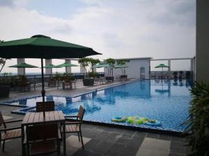 a large swimming pool with a table and an umbrella at Putri Hotel at Mydin Tunjong in Kota Bharu