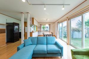 a large blue couch in a living room with windows at GuestHouse　YOU&I in Fujikawaguchiko