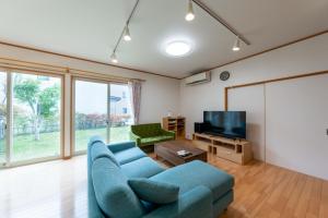 a living room with a blue couch and a tv at GuestHouse　YOU&I in Fujikawaguchiko