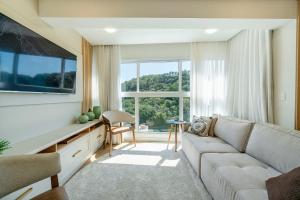 a living room with a couch and a large window at Riviera Concept Elegante Studio by Achei Camboriú in Cabeçudas