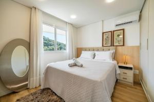 a bedroom with a large bed with a large window at Riviera Concept Elegante Studio by Achei Camboriú in Cabeçudas +38 photos