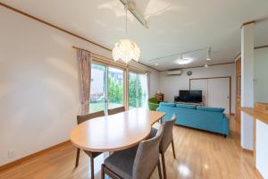 a dining room with a table and a blue couch at GuestHouse　YOU&I in Fujikawaguchiko