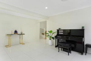 a living room with a piano and a table at 6BR House & Gym Walk to Moorebank Train Station in Moorebank