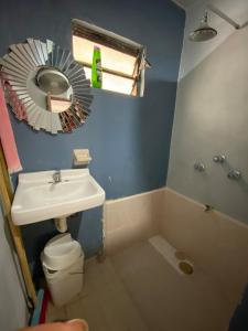 a bathroom with a sink and a toilet and a mirror at Casita Azul del mar, sencilla con fresca brisa in Chelem