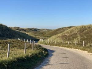 a dirt road with a fence on the side of a hill at Group home with sauna near the beach and sea in Julianadorp