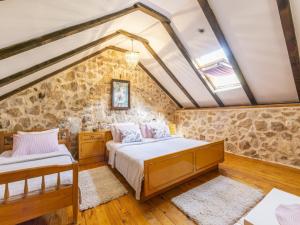 a bedroom with two beds and a stone wall at Rustical Resort Kokori i with Shared Outdoor Swimming Pool - One Bedroom Apartment with Terrace in Višnjica +28 photos